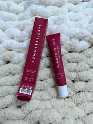 Summer Fridays Lip Butter Balm Cherry - Summer Fridays Lip Butter Balm i färgen Cherry kommer i en snygg vinröd tub med vit kork. Innehåller 15 g och ger läpparna en mjuk och återfuktad känsla med en hint av körsbärston. Förpackningen är modern och enkel att ta med i väskan.