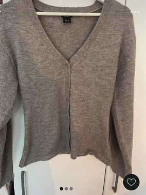 Beige kofta från Lindex, XS - Mysig beige kofta från Lindex i storlek XS. Koftan har v-ringning, knappar framtill och är långärmad. Perfekt för lager på lager och chill dagar. Materialet känns mjukt och är stickat för extra komfort.