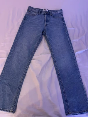 Blå raka jeans från Jack & Jones - Säljer ett par klassiska blå jeans från Jack & Jones. Modellen har rak passform, fem fickor och normal midja. Jeansen är tillverkade i slitstark bomull och har en snygg ljus tvätt. Perfekta till en avslappnad stil och funkar året runt.