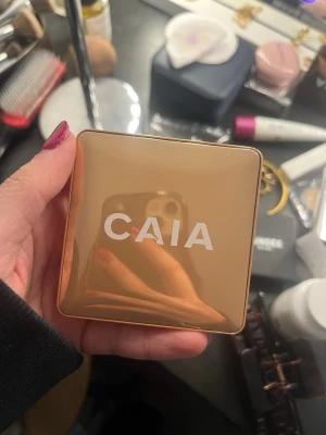 CAIA puder och highlighter duo - Säljer två CAIA-produkter i snygga fyrkantiga dosor, en i guld och en i silver. Perfekta för att skapa glow och definition i ansiktet. Lyxig metallisk finish på förpackningarna, smidiga att ha med i väskan. Passar dig som vill ha en fräsch look.