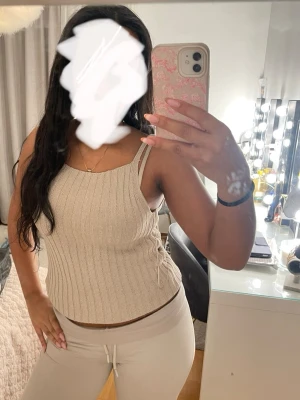 Beige ribbad linnetopp - Säljer en beige ribbad linnetopp med smala axelband och diskret snörningsdetalj i sidan. Toppen har en mjuk, stickad känsla och är perfekt för varma dagar. Enkel och stilren design som är lätt att matcha med olika outfits. Säljer även JEANSJACKAN för 45kr  eller båda för 80kr. Det funkar också att bara beställa jeansjackan för 45kr. 