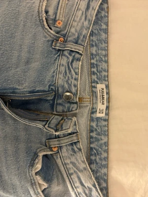 Ljusblå raka jeans från Pull&Bear - Säljer ett par ljusblå jeans från Pull&Bear med klassisk femficksdesign och raka ben. Jeansen har låg midja, dragkedja och knapp framtill samt bälteshällor. Tillverkade i jeansmaterial av bomull för en avslappnad vibe.