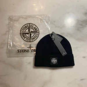 Sttone issland Mössa - Stilren ribbstickad mössa i mycket bra skick. Klassisk design med diskret patch framtill. Oanvänd, originaltags och förpackning medföljer. Perfekt till vardag och streetwear. One size – passar de flesta. Skickas snabbt.