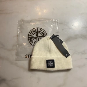 Sttone Issland Mössa - Stilren ribbstickad mössa i mycket bra skick. Klassisk design med diskret patch framtill. Oanvänd, originaltags och förpackning medföljer. Perfekt till vardag och streetwear. One size – passar de flesta. Skickas snabbt.