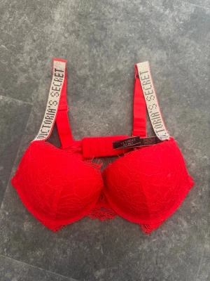 Röd spets-bh Victoria's Secret - Säljer en röd bh från Victoria's Secret med spetsdetaljer och vadderade kupor. Helt ny och plasten är på😍 Storlek 75c. Nypris är 1200kr