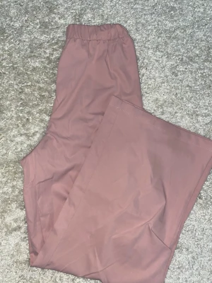 Rosa cargopants med fickor - Säljer ett par snygga cargopants i en rosa färg. Byxorna har elastisk midja och stora fickor på sidorna för en chill och praktisk look. Materialet känns mjukt och lätt, perfekta för en avslappnad stil. Passar både xs och s. Aldrig använd