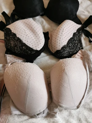 Prickig och spetsdetaljerad bh - Snygg väst i ljus färg med svarta prickar och dekorativa svarta spetsdetaljer längs kanterna. Västen har en feminin form och är perfekt för att ge outfiten en extra touch. Materialet känns mjukt och följsamt.