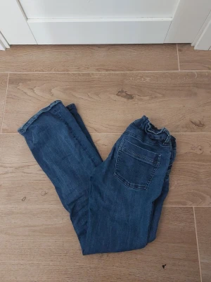 Blå jeans från Gina Tricot, strl 164 - Säljer ett par klassiska blå jeans från Gina Tricot i storlek 164. Jeansen har midja med knapp och dragkedja, samt bakficka. Man kan tighta till midjan som jag nu gjort❣️