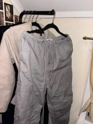 Grå cargobyxor från Sister - Säljer ett par grå cargobyxor från Sister med avslappnad passform. Byxorna har elastisk midja med snörning, stora sidofickor och är tillverkade i bomull. Perfekta för en chill och casual stil.