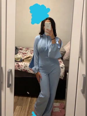 Elegant ljusblå jumpsuit med öppna ärmar - Elegant och stilren jumpsuit i en ljusblå nyans. Modellen har en markerad midja och raka, något vidare ben som ger en smickrande siluett. Ärmarna har en öppen/cut-out-design som ger ett modernt och genomtänkt uttryck utan att bli för mycket.  Passar utmärkt till fest, middag, student eller andra tillfällen där man vill vara välklädd och bekväm. Mjukt och följsamt material som sitter fint hela dagen/kvällen. Har bara använt den en gång så den är i mycket bra skick😍🦋