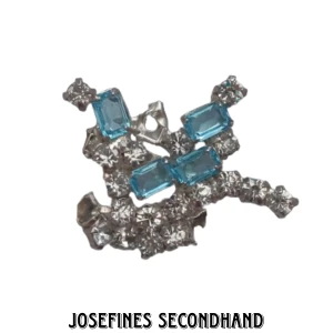 Glittrig brosch - Silver brosch med blå och vita kristaller. I använt skick. Skickas med brev, frakt 15 kr. Fri frakt vid köp av 3 eller fler smycken/smink prylar