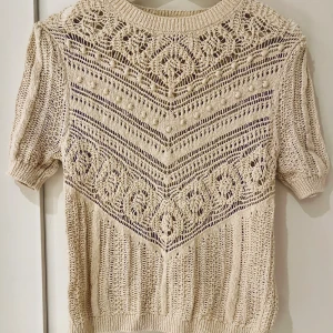 Stickad kortärmad topp från Zara  - En söt stickad topp med mönster och korta ärmar. 100 % bomull. Färgen är ljust creme/beige