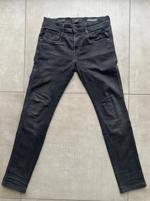 Svarta Replay Anbass jeans skinny fit - Säljer ett par svarta Replay Anbass jeans med skinny fit. Klassisk femficksmodell med snygga detaljer på fickorna och Replay-logga på bakfickan. Jeansen är i stretchigt material för extra komfort och har en modern, smal passform.