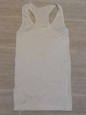 Vitt sportlinne - Säljer ett enkelt och stilrent vitt sportlinne med brottarrygg. Materialet känns mjukt och stretchigt, vilket gör den superbekväm att träna i. (Oanvänt)    !!endast swish +frakt!!