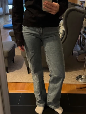 Straight leg jeans från Never denim - Säljer ett par ljusblå wide leg jeans från Never denim. De har regular midja, raka ben och klassisk femficksdesign. Jeansen är i bomull och har knäppning med knappar framtill. Perfekta för dig som gillar en avslappnad och trendig look. Storlek W26 L32 så ungefär S eller 36 och normallånga. 