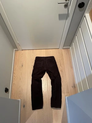 Weekday Manchesterbyxor  - Säljer ett par riktigt schyssta mörkbruna/vinröda manchesterbyxor. Byxorna har en snygg struktur i tyget och silverfärgade nitar vid fickorna. Perfekta för dig som vill ha en retro och stilren look.