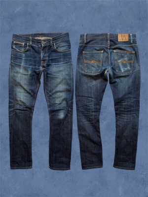 NUDIE DRY JAPAN SELVAGE - Ett par nudie jeans i materialet ”dry japan selvage” som fått en stört snygg fading! Modell ”Grim Tim” som sitter slimfit. Har några få lagningar som inte påverkar användningen. Reparerade på vissa ställen i framfickorna. Storlek 30/32 men gå alltid efter måtten. Hör av dig vid frågor! Mått: Ytterbenslängd - 102 cm, Midja - 41 cm, Benöppning - 17 cm