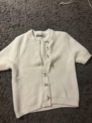 Vit kofta med rosettknappar från Zara - Vit mjuk kortärmad kofta med rosettknappar