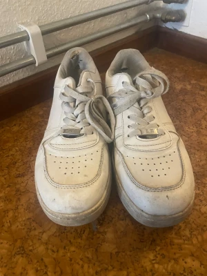 Vita sneakers med Los Angeles-tryck - Säljer ett par vita sneakers med coolt 'Los Angeles' tryck på hälen. Skorna har snörning, perforerad tå och platt sula. Materialet är skinn och insidan är fodrad med textil. Perfekt för dig som gillar streetstyle och vill sticka ut med detaljer.