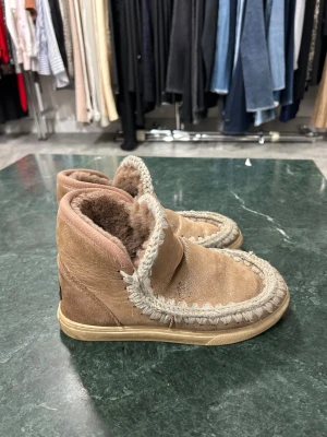 Beige boots från Mou med ullfoder - Säljer ett par beige boots från Mou med mjukt ullfoder och grova stickade detaljer runt kanten. Skorna har en platt sula och är tillverkade i mocka med insida av fluffig ull. Perfekta för kalla dagar och har en rund tå. Storlek 37 men passar bra på mig som brukar ha 38/39