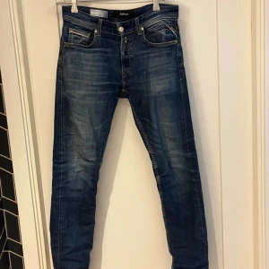 Replay Grover raka jeans blå - Snygga blå jeans från Replay, modell Grover med rak passform. Klassisk femficksdesign. Jeansen är tillverkade i denim och har en läderpatch bak i midjan. Perfekta för en avslappnad och stilren look. Den enda skavanken är att lappen där bak sitter lite löst 