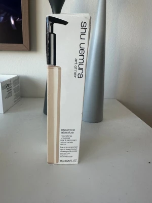 Shu Uemura Essence Absolue balm - Säljes pga. Felköp. Universal balm från Shu Uemura, Essence Absolue, med röd camelliafröolja. Kan användas på både hår och hud för återfuktning och glans. Kommer i en stilren beige pumpflaska, 150 ml. Perfekt för dig som vill ha multifunktionell produkt i badrumshyllan.