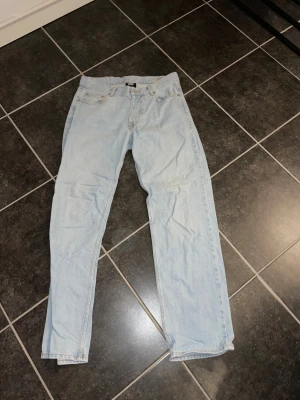 Ljusblå jeans från Sweet SKTBS, storlek 29 - Säljer ett par ljusblå jeans från Sweet SKTBS i klassisk femficksmodell. Jeansen har rak passform och normal midja, med snygga kontrastsömmar och en enkel design. Perfekt för dig som gillar skandinavisk streetstyle och vill ha ett par stilrena jeans.