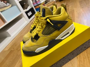 Nike Air Jordan 4 Retro gul - Nike Air Jordan 4 Retro sneakers i en fet gul färg med svarta och vita detaljer. Skorna har meshpaneler, snörning och den klassiska Jumpman-loggan på hälen. Ovandelen är i skinn och sulan har synlig Air-enhet. Perfekt för dig som vill sticka ut med din sneakerstil.