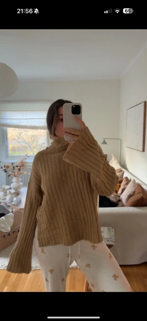 Beige ribbad polotröja med slits - Säljer en beige polotröja med ribbad struktur och långa, lite vidare ärmar. Tröjan har en hög krage och slitsar på sidorna vilket ger en chill och avslappnad vibe. Perfekt för lager-på-lager under höst och vinter. Materialet är stickat och mjukt.