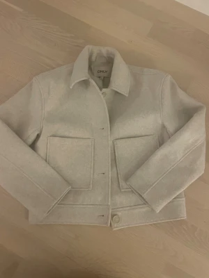 Beige jacka från ONLY - Snygg beige jacka från ONLY med krage och framfickor, sällan använd och finns även en extra knapp på innsidan. Storlek 152.