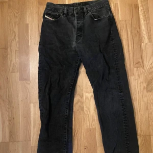 Svarta Diesel jeans straight fit - Jeans i urtvättat svart från Diesel i klassisk straight/regular fit. Minns inte vilken modell men sitter liknande de på bilden. De är mycket sköna men var lite för baggy för min smak. Nypris 1800kr