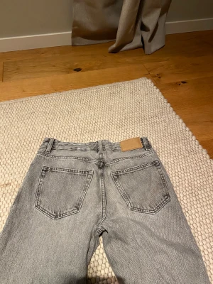 Grå straight jeans från Zara - Snygga grå jeans från Zara med klassisk femficksdesign och raka ben. Jeansen har hög midja och är tillverkade i slitstarkt bomullsmaterial. Perfekt tvättad look och neutrala sömmar, passar dig som gillar enkel och stilren denim. 