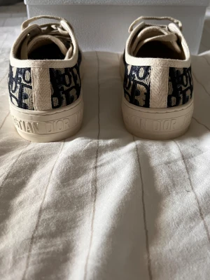 Dior walk N dior - ÄKTA. PRIS KAN DIKSUTERAS! Snygga Dior Oblique sneakers med blått och beige mönster, klassisk snörning och rund tå. Skorna har en platt sula med stjärndetalj undertill och tydlig Christian Dior-logga på både plös och häl. Tillverkade i canvas med exklusiv känsla.