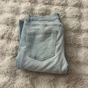 Bootcut ljusblå jeans  - Snygga ljusblå bootcut jeans med klassisk femficksdesign och bälteshällor. Jeansen har raka ben med lätt utsvängning och är tillverkade i mjukt denimtyg. Perfekta för dig som gillar retrovibbar och vill ha en chill look.