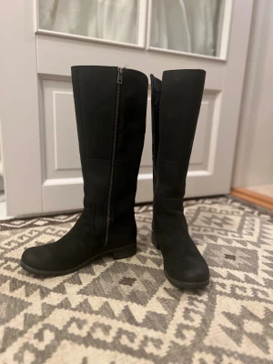 Svarta stövlar Timberland Earthkeepers - Snygga svarta stövlar från Timberland, knähöga med rund tå och diskret grovmönstrad sula. Stövlarna har dragkedja på insidan och är tillverkade i mocka. Funkar både höst och vinter, allround både i stan och i naturen. Passar även mig med strl 38, får plats med varmfodrad sula för den som önskar komplettera. Mycket sparsamt använda. 