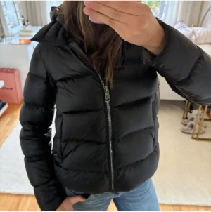 Svart dunjacka från COLMAR - Säljer en svart dunjacka från Colmar med huva. Jackan har en defekt men ingen man märker av, därav pris. Skriv för mer bilder och info!🩷