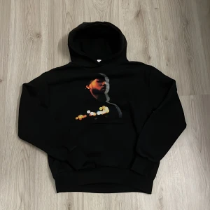 partynextdoor - Svart hoodie med stor huva och tryck på bröstet i färg med motiv av en person och bokeh-ljus. På ryggen står det 'WELCOME TO THE PARTY' i vit text och en guldfärgad signatur under. Hoodien har ribbade muddar och klassisk passform.