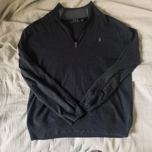 Grå Ralph Lauren tröja  - Mörkgrå långärmad tröja från Ralph Lauren med halvzip och diskret broderad logga på bröstet. Stilren design som är lätt att matcha och alltid ger en clean look. Perfekt för vinterhalvåret när man vill vara både varm och snygg!  📏 Storlek: M ✨ Skick: Bra skick, välvårdad och utan skador. 🧵 Material: Bomullsmix – mjuk och bekväm.                ✅ Pris kan diskuteras