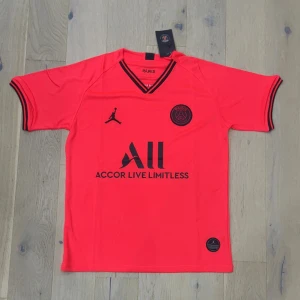 PSG kortärmad fotbollströja röd - Snygg PSG fotbollströja i röd färg med svarta detaljer och loggor. Kortärmad modell med V-ringad hals och svarta ränder på ärmsluten. Tillverkad i lätt och ventilerande polyester, perfekt för träning eller match. Jordan-logga och Paris Saint-Germain-emblem på bröstet.