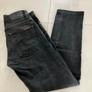 Nudie Jeans Grim Tim W29 L30 - Svarta jeans från Nudie Jeans, deras storsäljare Grim Tim slim straight jean. Klassisk femficksmodell med svarta sömmar och diskret logga på bakfickan. Nyskick, jeansen har använts en gång pga storlek (felköp). Nypris 1599,- 
