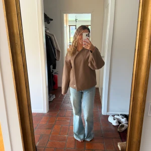 Brun omlott kappa  - Säljer en snygg brun kappa i omlottmodell med stora knappar framtill. Jackan har en rak och loose passform med långa ärmar och är tillverkad i ett mjukt material som känns lite ulligt. Perfekt för dig som gillar stilrena och minimalistiska plagg.