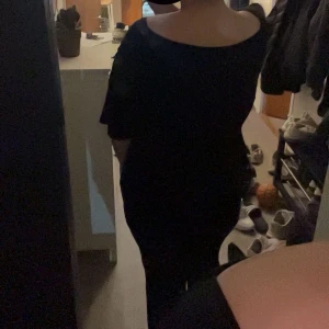 Svart v-ringad klänning - En svart klänning med v-ringning och korta ärmar. Modellen är enkel och stilren med en rak passform som sitter snyggt på kroppen. Perfekt för dig som gillar minimalistisk stil och vill ha något klassiskt i garderoben.