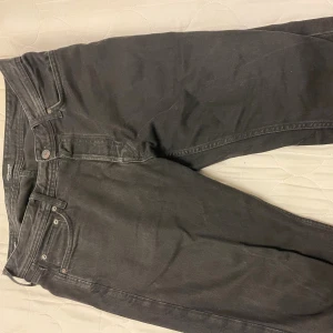 Svarta relaxed jeans från Jack & Jones - Svarta jeans från Jack & Jones, modell Relaxed Chris. Klassisk femficksdesign med raka ben och avslappnad passform. Jeansen är tillverkade i slitstarkt bomullsmaterial och har metallnitar och knappstängning. Perfekt för en chill och stilren look.