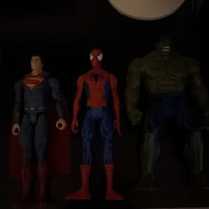 Superhjälte actionfigurer (Superman, Spiderman, Hulk) - Tre actionfigurer: Superman, Spiderman och Hulk. Figurerna är i gott skick med mindre spår av användning. Perfekt för samlare eller barn som älskar superhjältar. Inga synliga större defekter, färgerna är klara och detaljerna tydliga.
