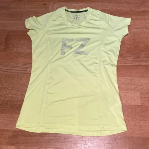 FZ Forza - Gul sportig t-shirt / Badminton  - Fräsch gul t-shirt från FZ Forza med stort FZ-tryck på bröstet. Tillverkad i funktionsmaterial som andas, perfekt för träning. Kortärmad modell med rund hals och figurnära passform. Snygg och sportig vibe!
