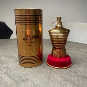 Jean Paul Gaultier Le Male Elixir 125ml - Perfekt för vintern❄️ ‼️bara testad | jag har tappat bruket så att den blivit en liten buckla (se fjärde bilden) och korken  kan inte åka ner hela vägen, men inget som på verkar doft eller användning‼️därför säljer jag den till ett rimligt pris💛 Snygg och lyxig parfym i guldigt utförande från Jean Paul Gaultier. Le Male Elixir sticker ut med sin unika design och är perfekt för dig som vill ha något extra i samlingen. Perfekt för dig som gillar statement-flaskor.
