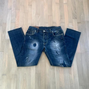 Dondup George  - Säljer ett par blå Dondup jeans med slitningar. Jeansen är i fint skick 8/10✅ En liten defekt vid skrevet dock ej synlig vid användning. Hör av dig vid minst föndering!