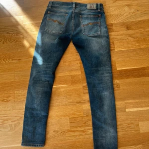 Nudie Jeans Skinny Lin blå jeans 32/32 - Säljer ett par Nudie Jeans Skinny Lin i klassisk blå tvätt. Jeansen har skinny fit, fem fickor och snygga slitningar. Tillverkade av 98% ekologisk bomull och 2% elastan för extra stretch och komfort. Perfekta för dig som gillar en smal siluett.