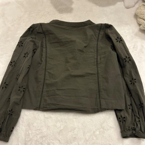 Olivgrön blus med broderade detaljer - .