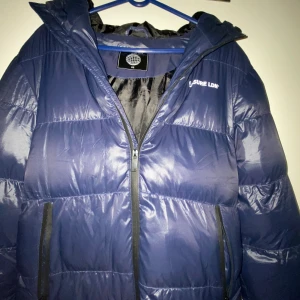 Blå pufferjacka från Closure LDN XS - Snygg mörkblå pufferjacka från Closure LDN i storlek XS. Jackan har huva, två sidofickor med dragkedja och en clean design med diskret logga på bröstet. Perfekt för kalla dagar med sin fluffiga och quiltade look. Använd jätte lite och ny pris ca 1000kr. Priset kan diskuteras.